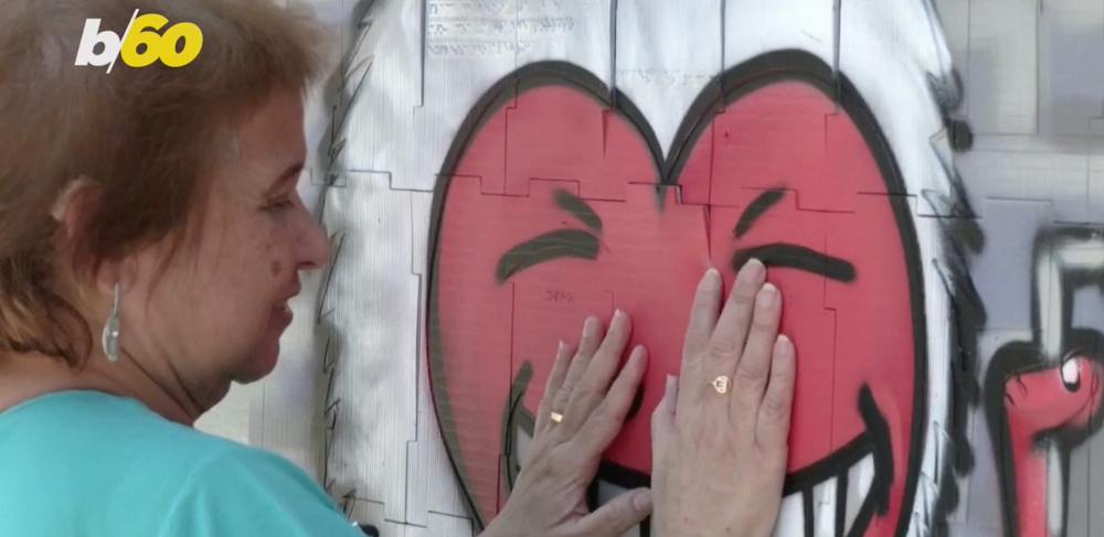 A woman in Brazil touching a wall painted with graffiti art.