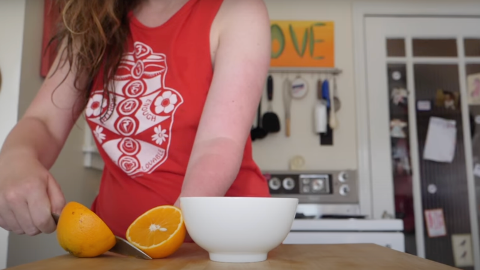 Screenshot of Stump Kitchen's video where Alexis is cutting an orange in half.