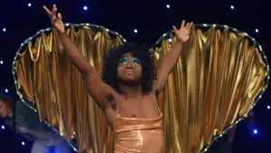 Francis Majekodunmi as Lady Francesca in Girl Meets Boy, wearing a sequinned gold dress and bright blue eyeshadow.