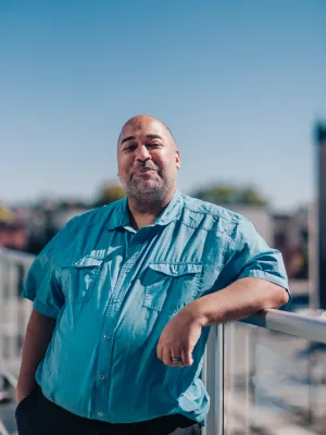 Velvet Wells stands outside, wearing a blue shirt, smiling at the came