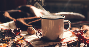 A coffee cup sits on a quilted tablecloth, steam billowing out of the mug.